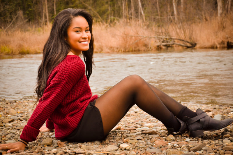 African American senior girl portrait in the fall along a river.