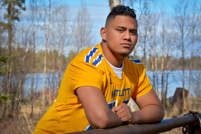 Samoan senior guy in football jersey posing for senior portraits.