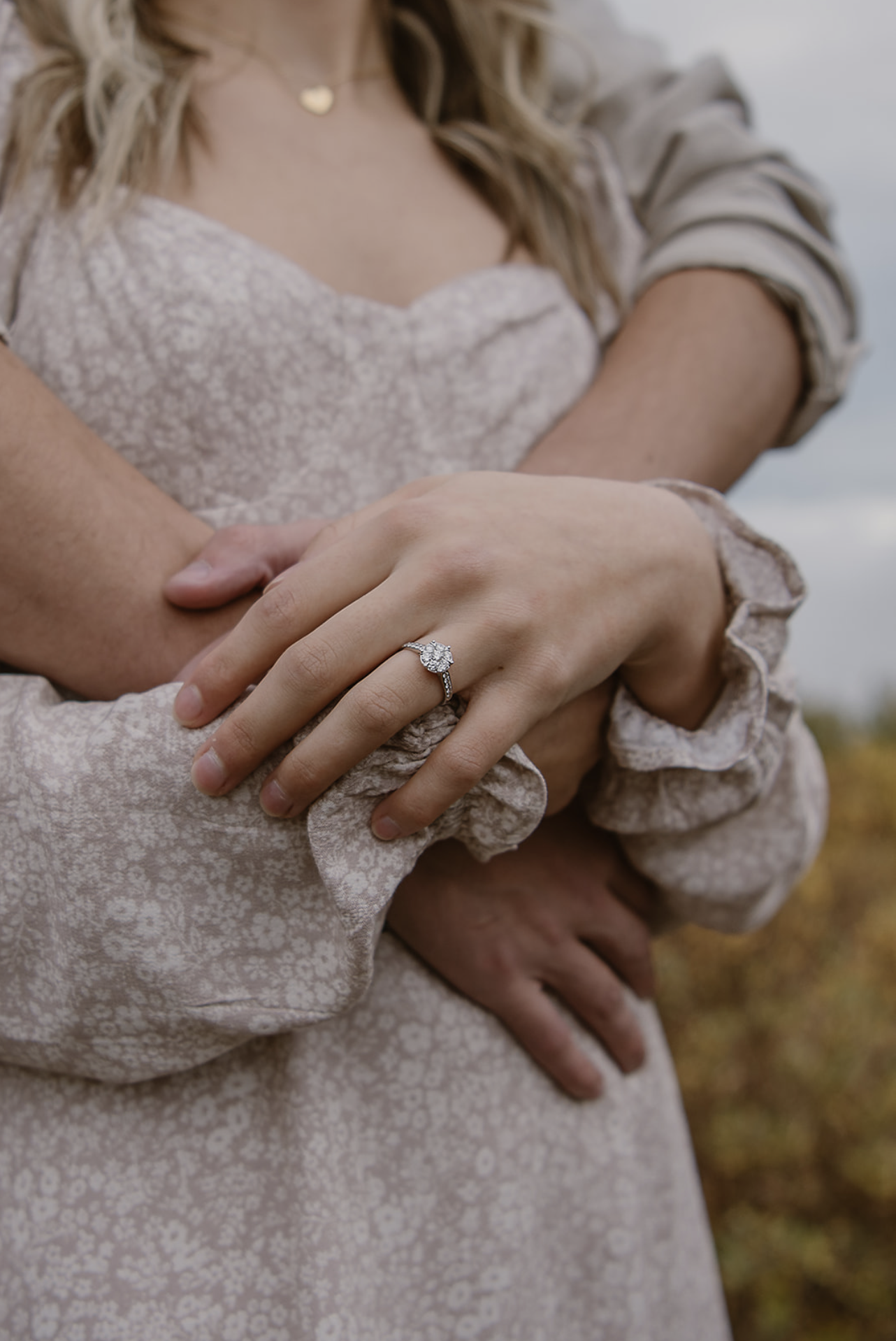 Alaska Bridal Closet rentals. Closeup of engagement ring in front of couple hugging